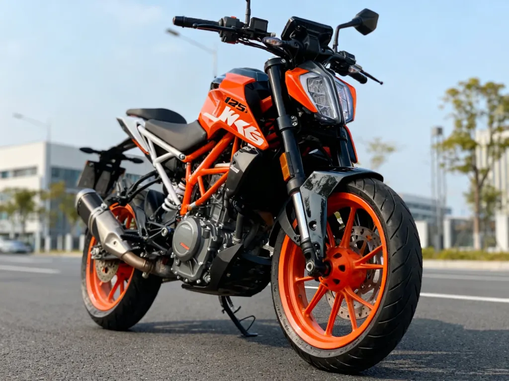 KTM Duke 125 z przodu na czystym asfalcie miasta, wyeksponowane felgi, hamulce i silnik w pomarańczowo-czarnej kolorystyce